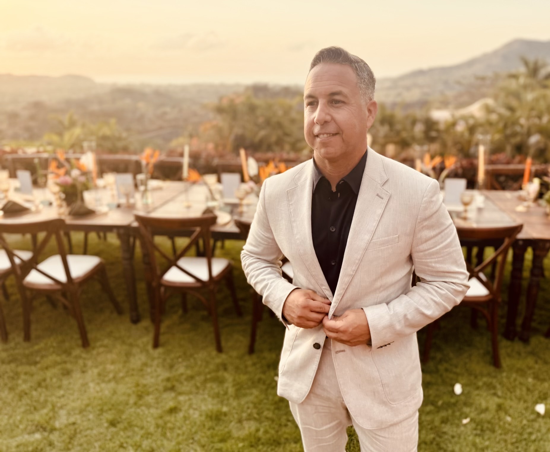 Michael Mendoza in a linen suit at an outdoor event at golden hour
